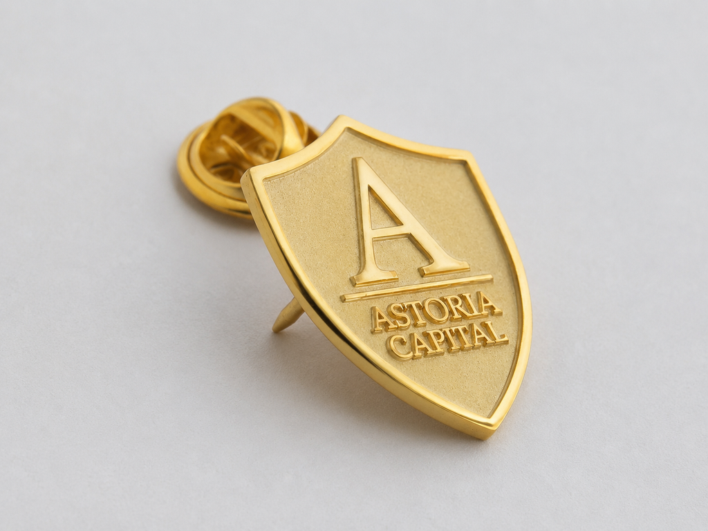 Angled view of a custom brass shield lapel pin with gold-tone electroplated finish