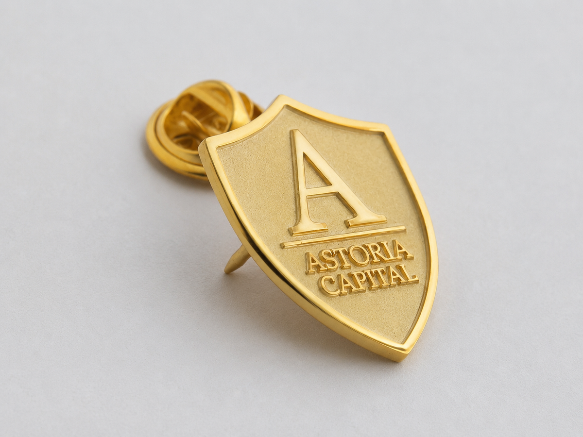 Angled view of a custom brass shield lapel pin with gold-tone electroplated finish